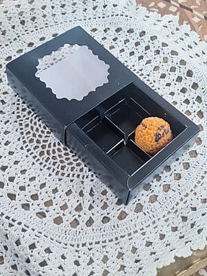 Alt Text: Black drawer box with clear window holding a laddoo candle in 4 cavities